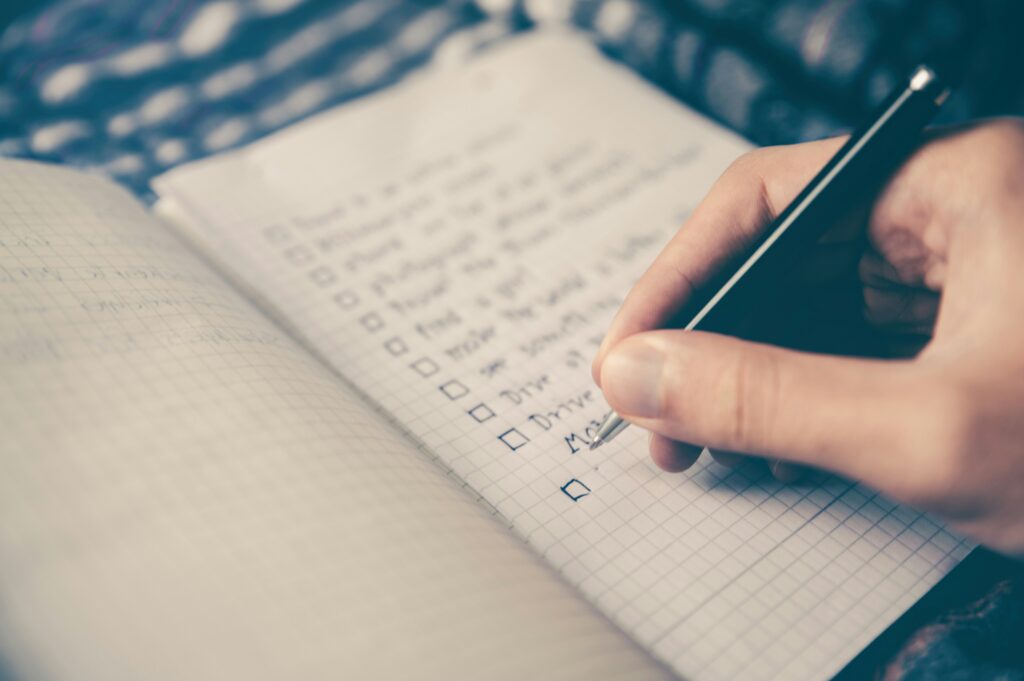 Hand writing in a checklist notebook.